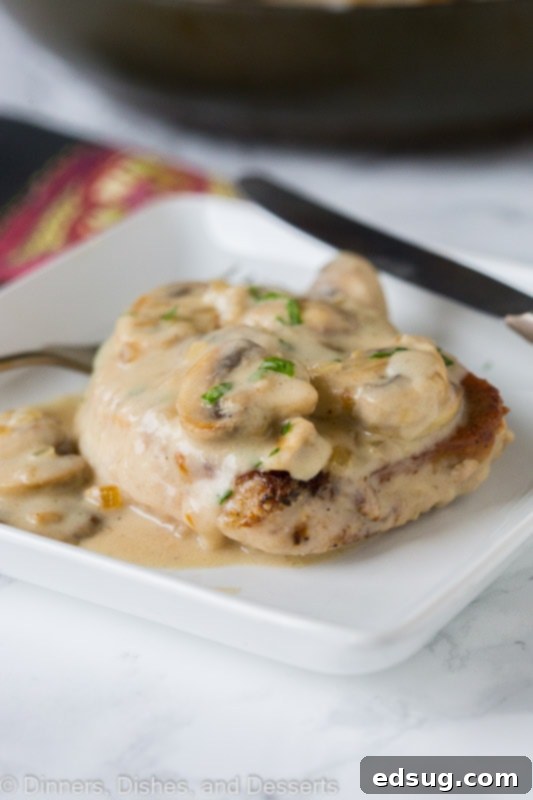 A smothered pork chop topped with mushroom gravy on a plate.