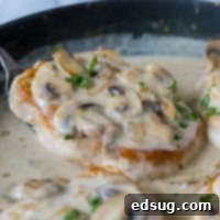 Close up of smothered pork chops with mushroom gravy in a skillet.