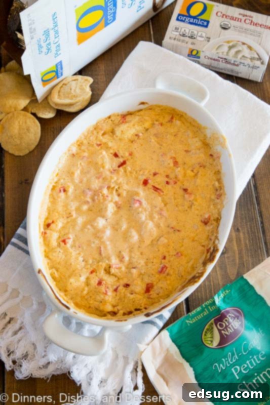 Warm and bubbly spicy shrimp dip in a rustic baking dish on a wooden table, ready to be served