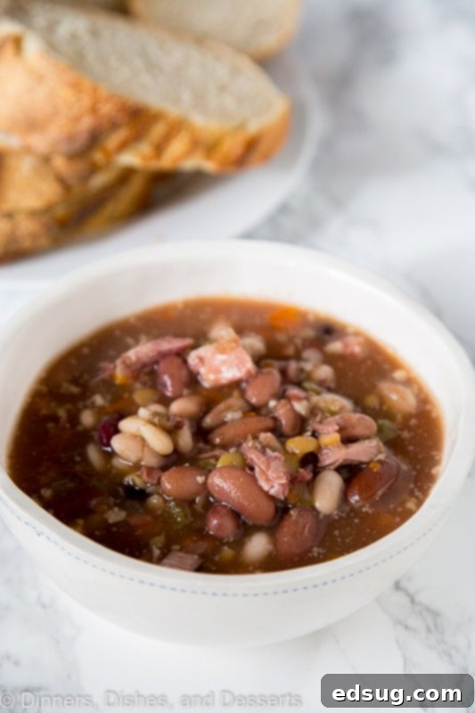 A bowl of Ham and Bean Soup ready to be enjoyed, served with fresh herbs.