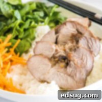 Cantonese BBQ Pork 2 Close up of sliced char siu pork in a bowl on top of rice with carrots and spinach