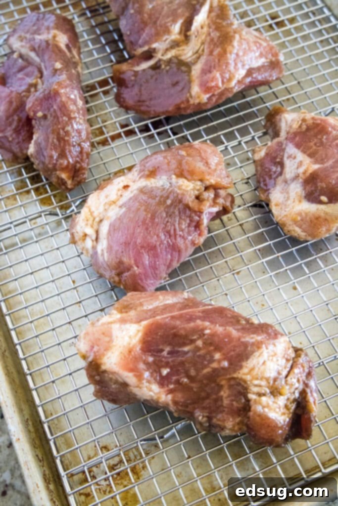 This easy char siu pork recipe is tender, juicy, and loaded with your favorite Chinese flavors like hoisin and five-spice powder. Overhead view of five pieces of marinated pork on a wire rack on a baking sheet