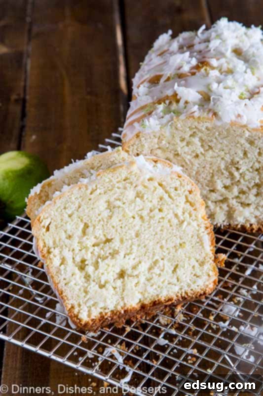 A single slice of moist coconut lime quick bread on a white plate, showcasing its tender crumb and glaze.