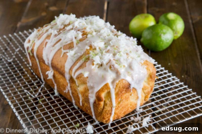 Close-up of a Coconut Lime Quick Bread loaf on a cooling rack, showing the texture of the glaze and coconut garnish.
