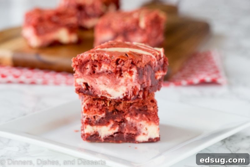 Decadent Red Velvet Cheesecake Brownies 4 A single square of red velvet cheesecake brownie on a white plate, highlighting the distinct red and white swirled layers.
