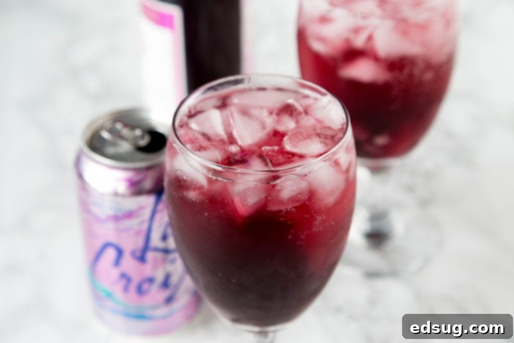 A glass of red wine spritzer with La Croix can in the background
