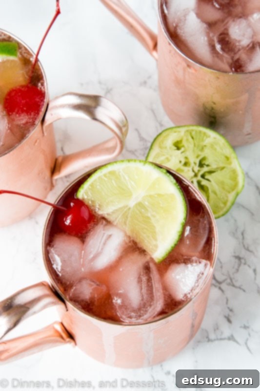 A close up of Cherry Lime and Moscow mule in a glass with lime slices