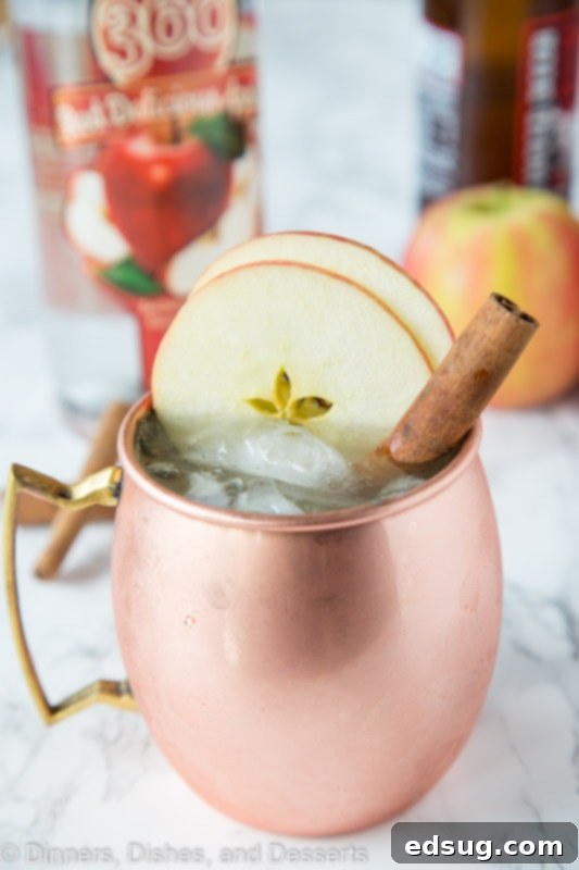 Apple Cider Moscow Mule in a copper mug, garnished with apple slices and a cinnamon stick