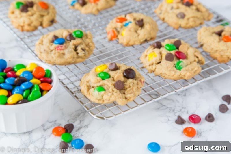 Six soft monster cookies arranged on a cooling rack, showing off their various mix-ins.