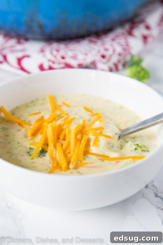 A steaming bowl of creamy homemade broccoli cheese soup with a spoon, ready to be enjoyed.