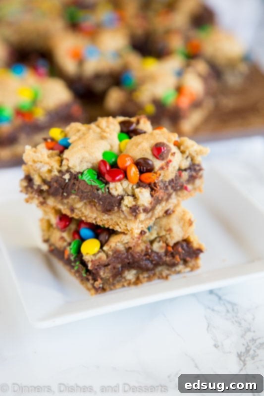 Close-up of a stack of M&M Chocolate Oat Bars with a rich fudge layer and colorful M&M candies