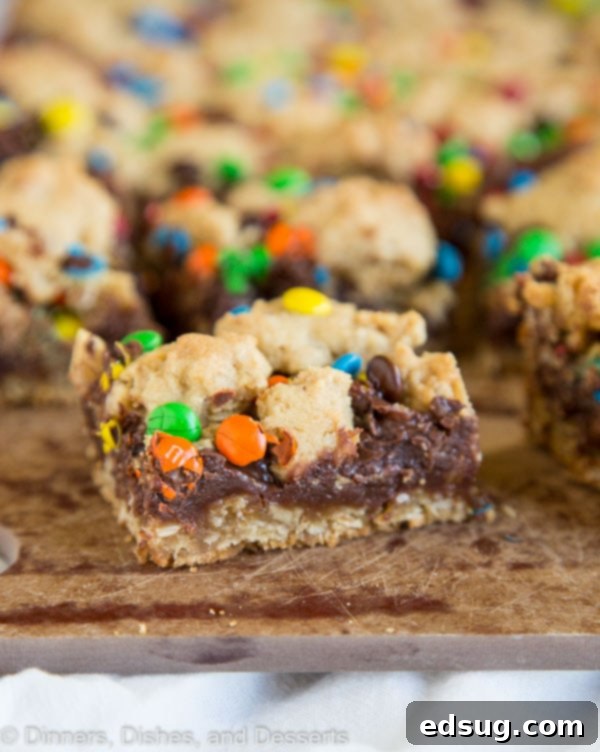 A close-up of a freshly baked pan of M&M Chocolate Oat Bars, showcasing the creamy fudge and crumbly oat topping