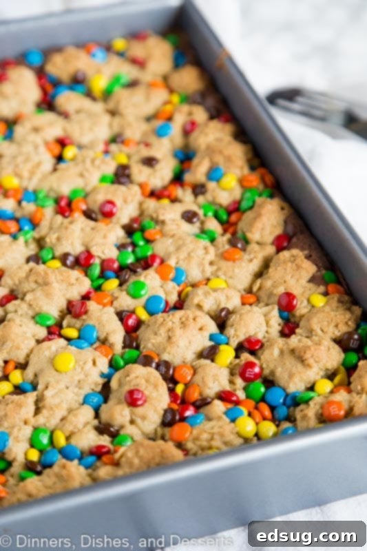 An overhead shot of a pan filled with M&M Chocolate Oat Bars, fresh out of the oven, with the M&M's perfectly set