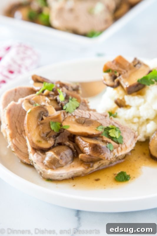 A perfectly cooked Instant Pot Pork Tenderloin, sliced and served with a rich mushroom sauce on a dinner plate, ready to eat.