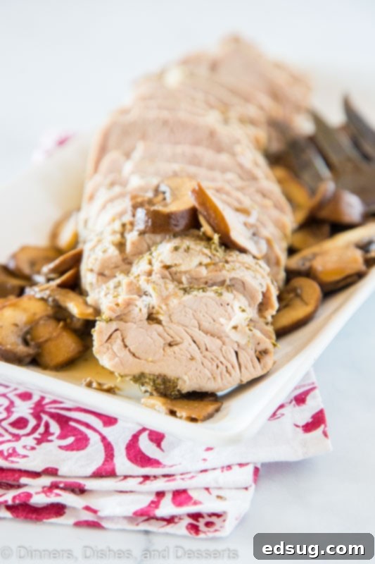 Close-up of succulent sliced pork tenderloin, perfectly cooked and topped with tender sautéed mushrooms, served on a white plate, highlighting its juiciness and the savory sauce.