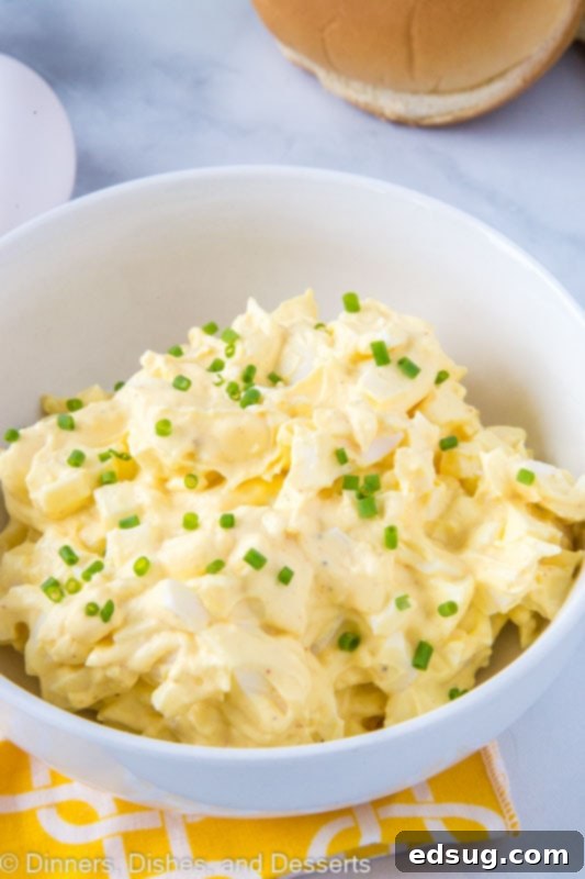 A beautifully presented bowl of creamy egg salad garnished with fresh herbs