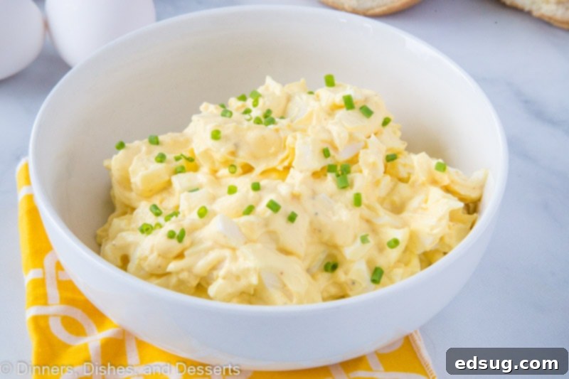 A close-up shot of a bowl of fresh egg salad garnished with vibrant chives