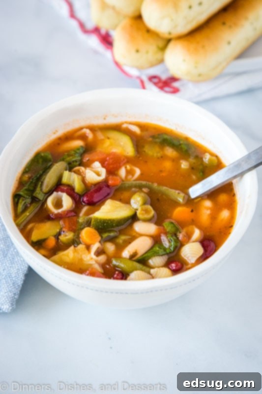 Olive Garden's Hearty Minestrone Soup 4 A close-up shot of a steaming bowl of vegan minestrone soup, brimming with pasta shells and a colorful mix of vegetables, perfect for a healthy and satisfying meal.