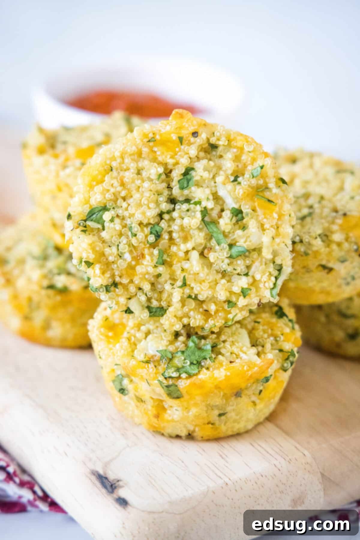 Golden brown quinoa bites on a wooden cutting board, garnished with fresh parsley and ready to be served as a healthy snack or appetizer.