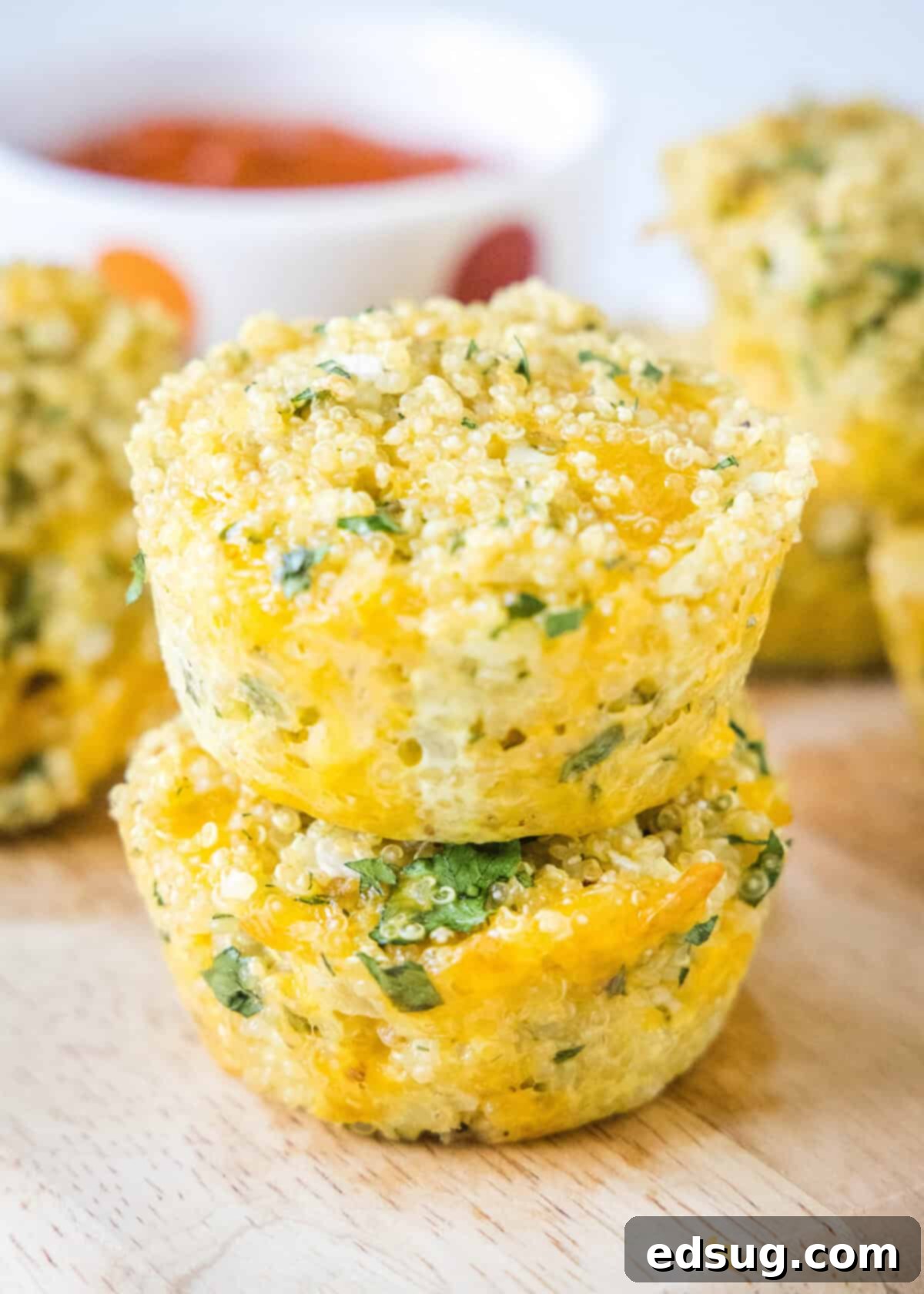 A stack of golden, herb-infused quinoa bites on a rustic cutting board, showcasing their appealing texture and snackable size.