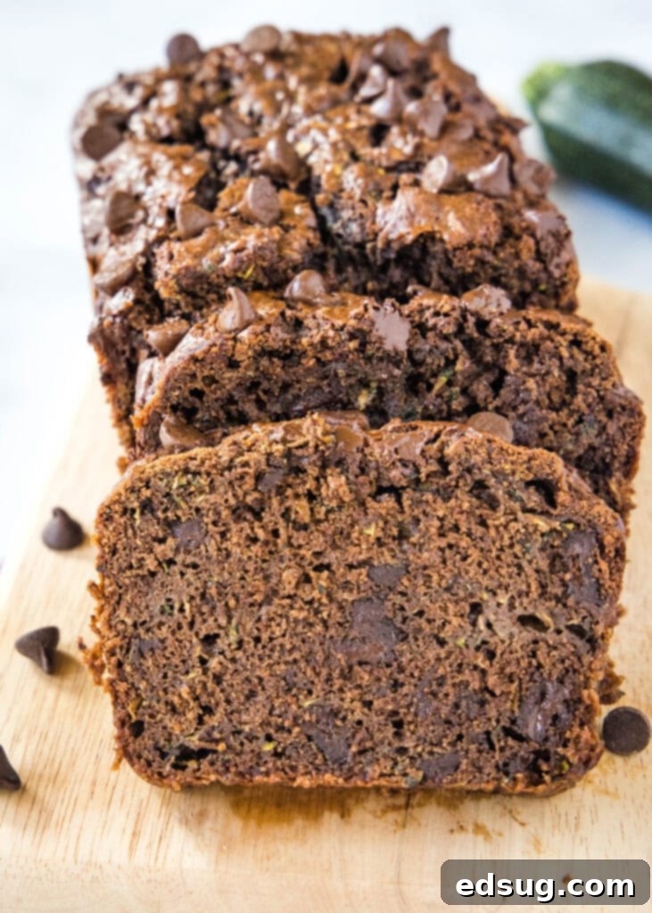 Sliced double chocolate zucchini bread on a rustic cutting board, showcasing its moist texture and chocolate chips.