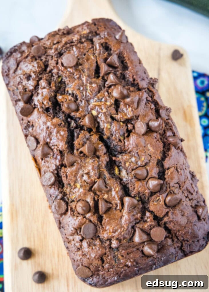 Close-up shot of a full loaf of chocolate zucchini bread on a cutting board, ready to be sliced.