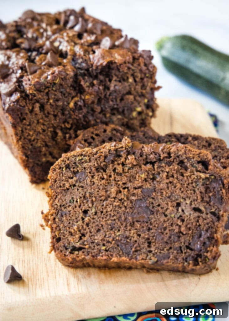 Perfectly sliced double chocolate zucchini bread on a wooden cutting board, highlighting its rich color and moist crumb.