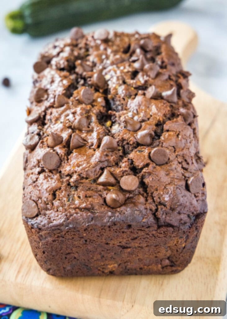 A beautifully baked loaf of double chocolate zucchini bread, unsliced, showcasing its rustic top crust.