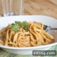 A close-up shot of Asian Peanut Noodles in a bowl with a fork, ready to eat.