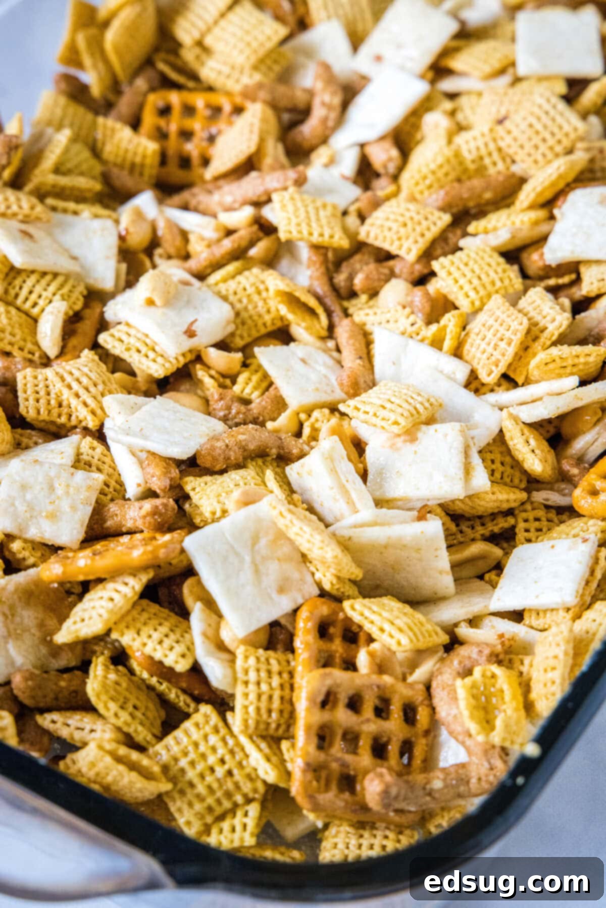Fiesta Taco Crunch 4 A freshly baked batch of Taco Snack Mix cooling in a glass baking dish, its golden brown pieces and spices clearly visible, promising a delicious crunch.