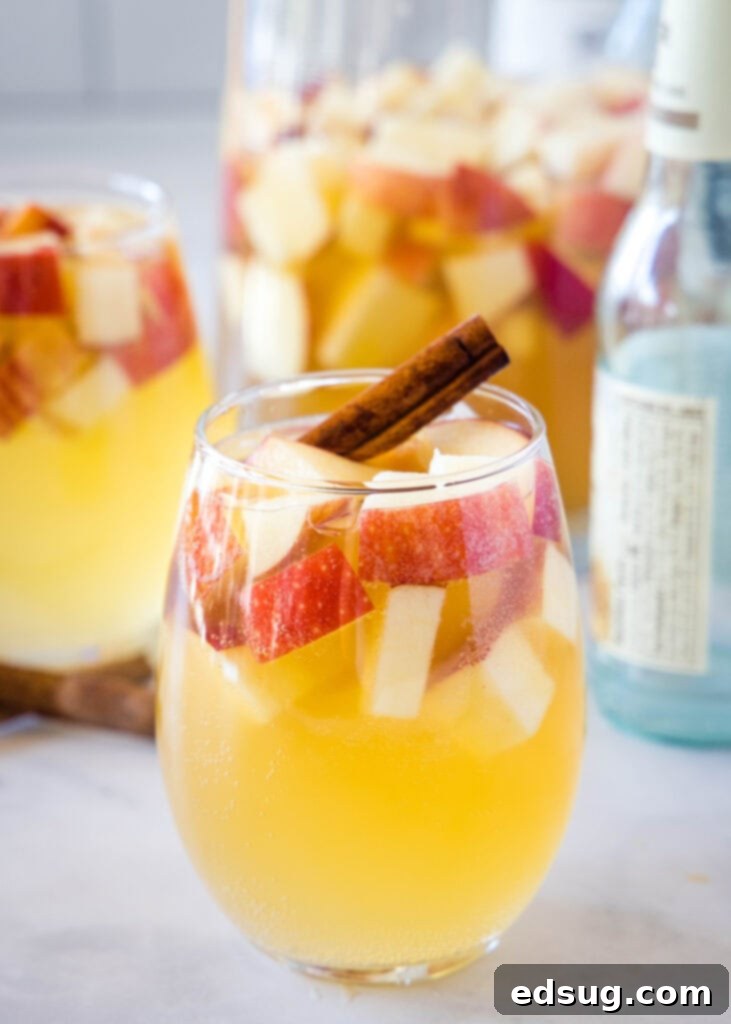 glass of fall sangria full of apples and a cinnamon stick, garnished beautifully