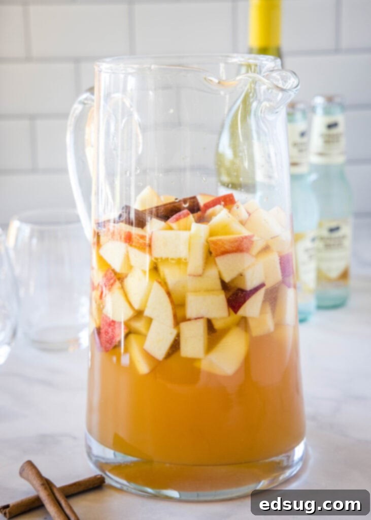 a pitcher of fall sangria with apples and cinnamon sticks