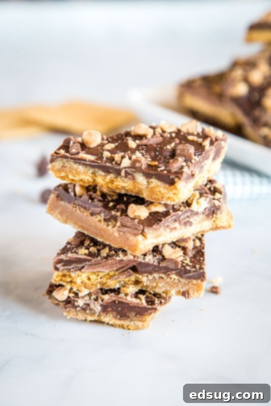 Quick Graham Cracker Toffee Recipe 2 Buttery Graham Cracker Toffee, also known as Christmas Crack, on a baking sheet, topped with melted chocolate and sprinkles, ready to be chilled and cut.