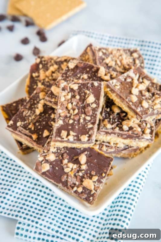 Quick Graham Cracker Toffee Recipe 3 Close-up of golden-brown Graham Cracker Toffee, topped with smooth melted chocolate and decorative toffee bits, arranged on a serving plate.