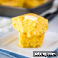 A piece of cornbread with butter on a plate, with Bread and Cornbread
