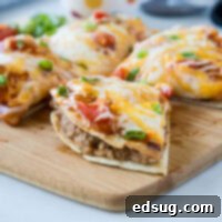 A perfectly sliced homemade Mexican Pizza, showcasing its layers of seasoned beef, refried beans, and cheese between crispy tortillas.