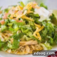 A close-up view of a vibrant Cafe Rio Chicken Tostada, piled high with fresh ingredients.