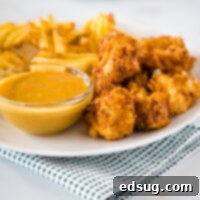 Crispy Chick-fil-A Chicken Nuggets served on a plate with golden fries and dipping sauce.