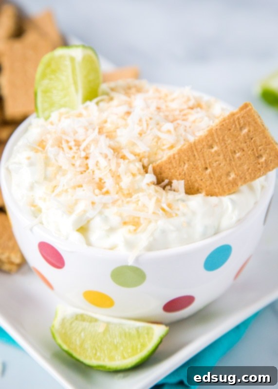 Creamy Coconut Lime Cheesecake Dip 2 Cheesecake dip with toasted coconut and lime wedge in bowl with graham crackers, ready to be served
