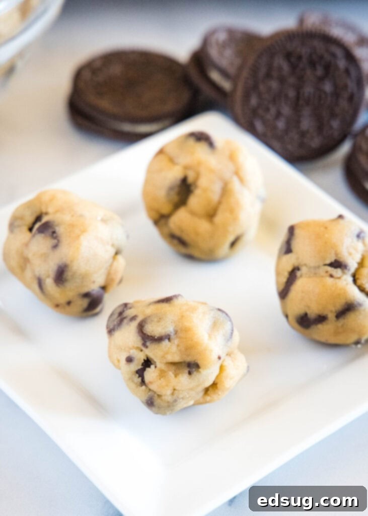 Chocolate Chip Cookies with an Oreo Center 4 Balls of chocolate chip cookie dough ready for stuffing, with a few Oreos in the background.