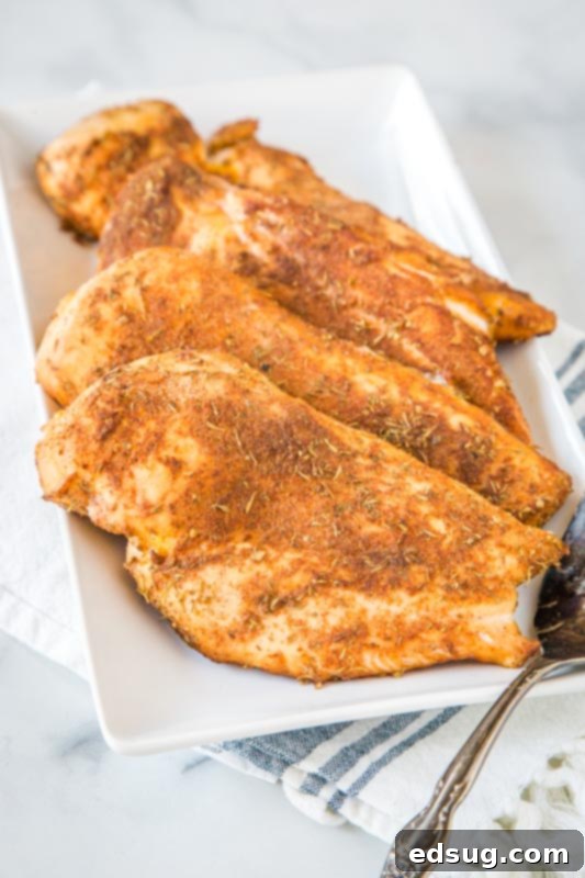White platter displaying several perfectly smoked chicken breasts, ready to be sliced and served.