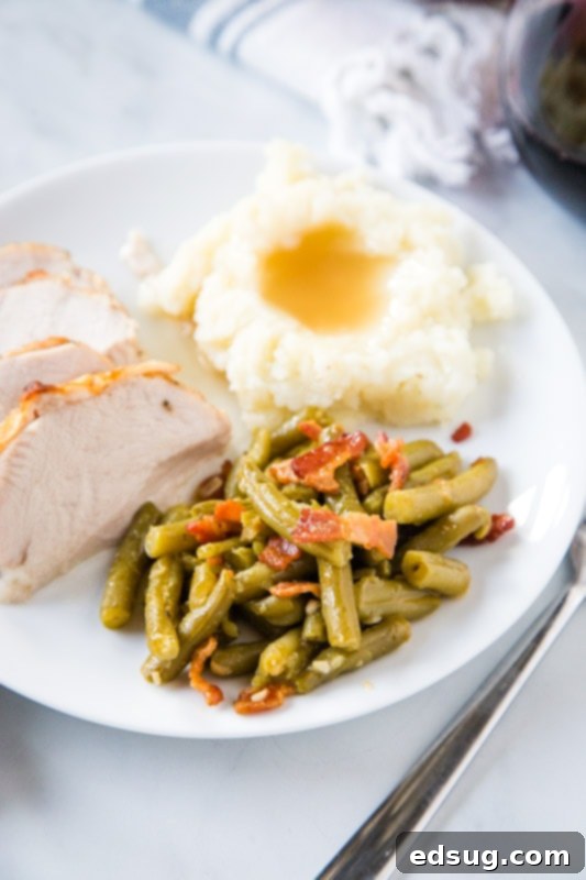 Hearty holiday plate featuring green beans with bacon, roasted turkey, and mashed potatoes