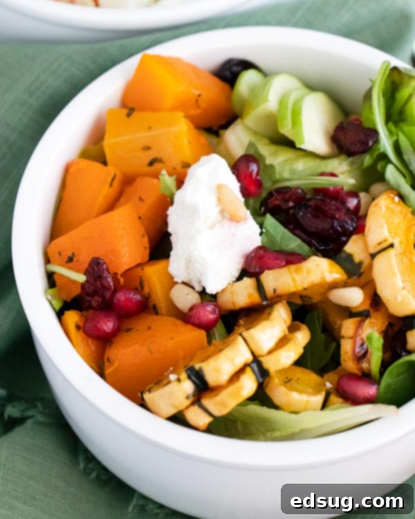 Looking down on a vibrant bowl of Roasted Squash and Goat Cheese Salad, filled with colorful ingredients.