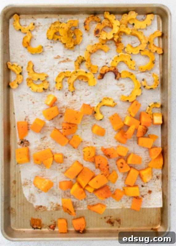 Perfectly roasted butternut and delicata squash pieces arranged on a baking tray.