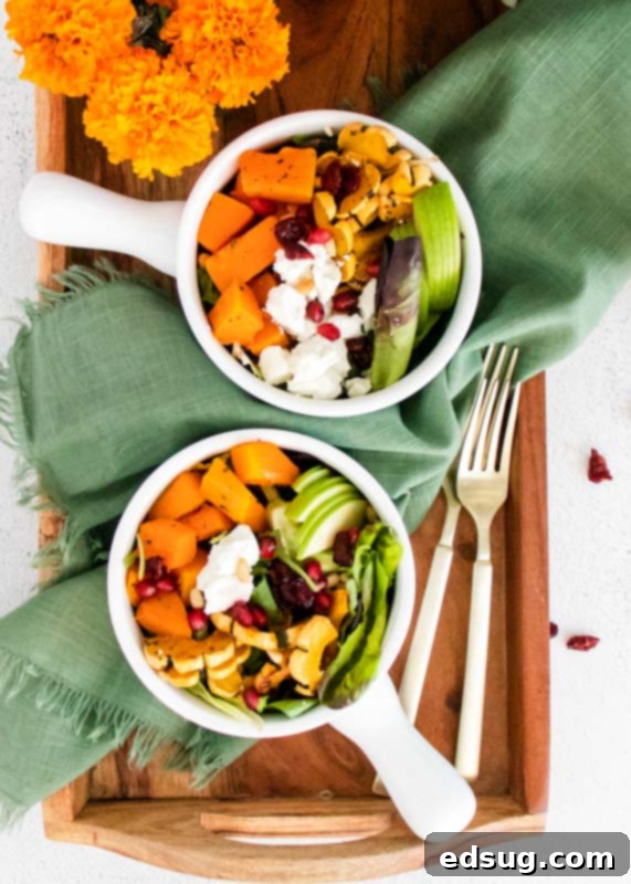 Two exquisite bowls of Roasted Squash and Goat Cheese Salad artfully presented on a wooden tray.