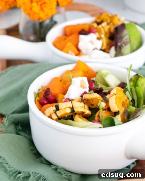 A single white bowl of Roasted Squash and Goat Cheese Salad, beautifully garnished with fresh flowers nearby.