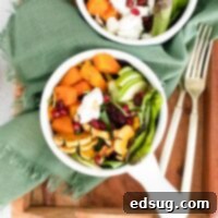Close up of a vibrant roasted squash and goat cheese salad in a white bowl.