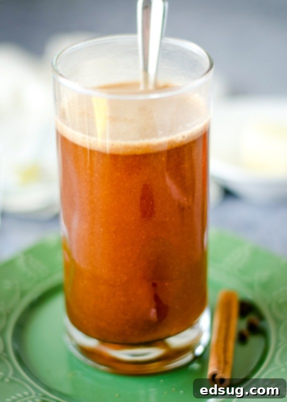 Close-up of hot buttered rum being stirred in a mug, showing the butter melting and spices dissolving