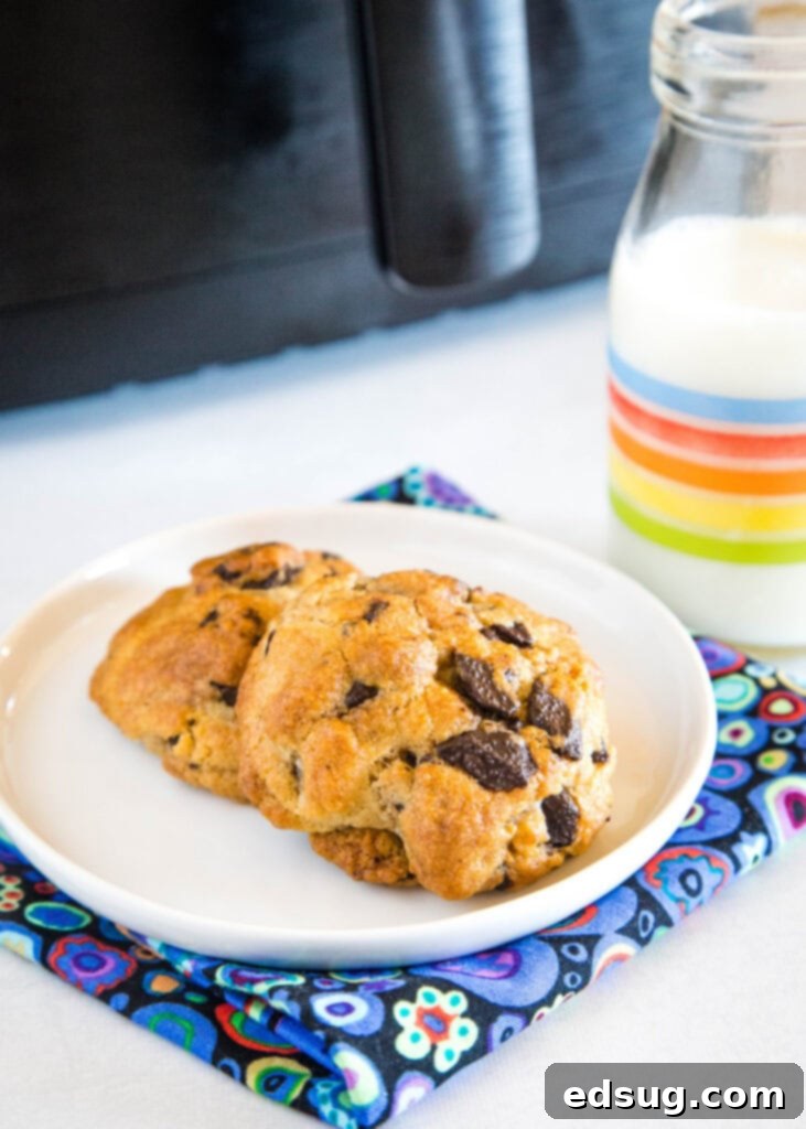 Four perfectly baked chocolate chip cookies served on a white plate, showcasing their soft centers and crispy edges.