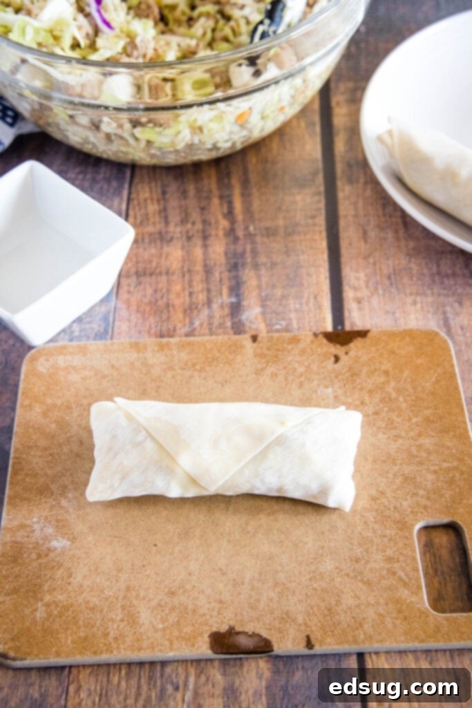 Golden Crispy Air Fryer Egg Rolls 8 The final step of rolling up an egg roll wrapper tightly to complete the wrap.